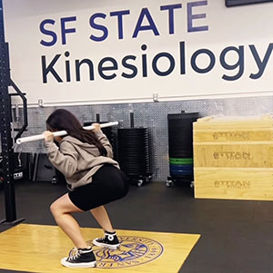 woman demonstrates squats in gym