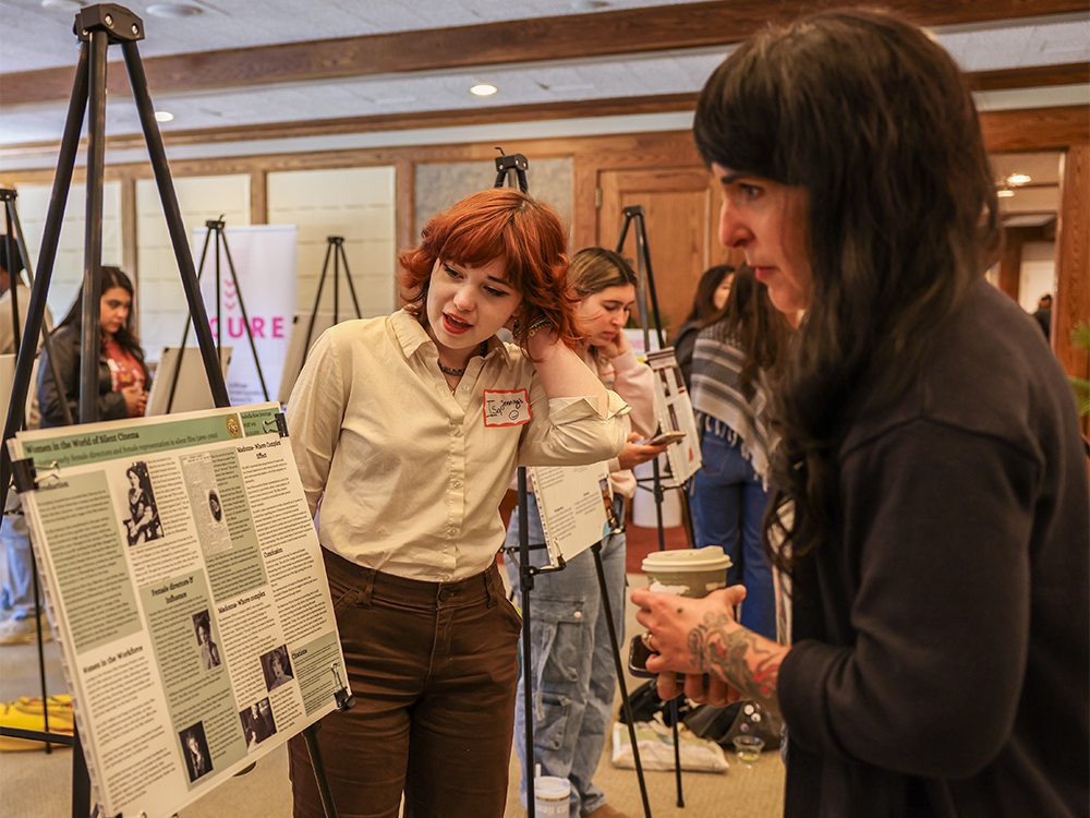 Student showing faculty her research poster at LCA research showcase