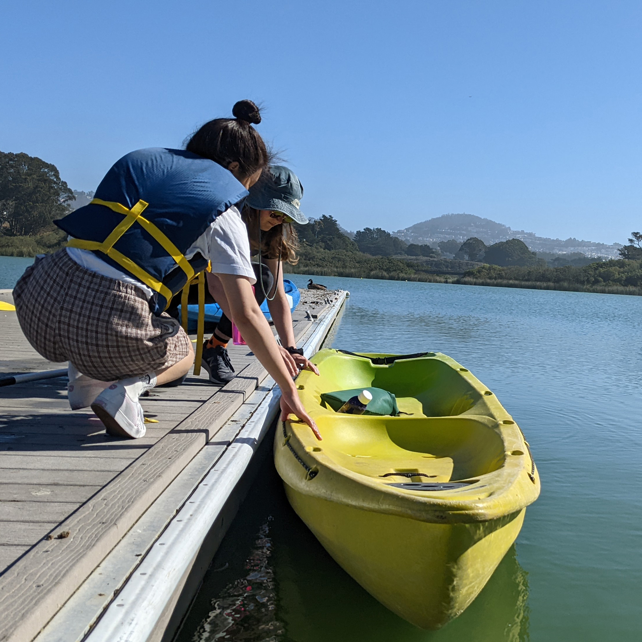 Two students pulling a kayak to dock