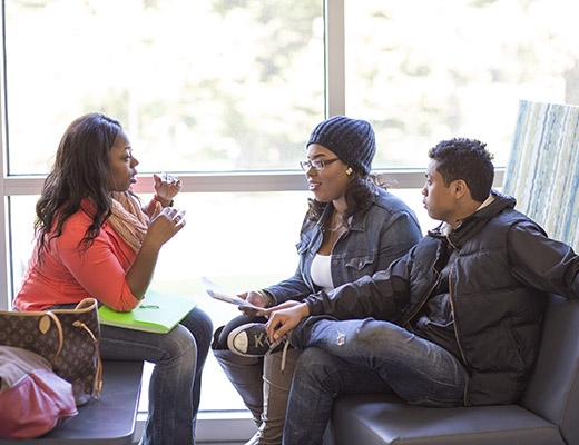 three students talking in library